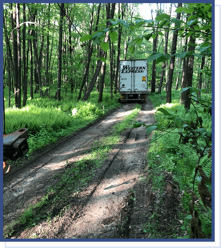 A truck driving down the road in the woods.